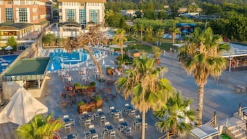 A resort with a swimming pool, outdoor seating, and palm trees.