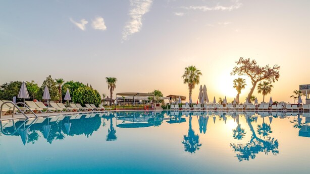 A swimming pool with lounge chairs and umbrellas, surrounded by palm trees and a clear sky. - Armas Gul Beach - All Inclusive (Kemer)