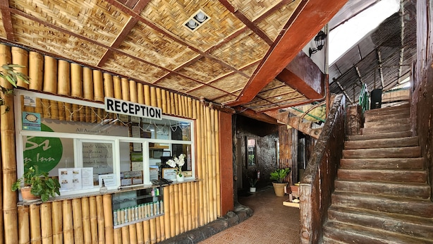 A reception area with a bamboo wall, a reception desk, and a staircase. - MB's Garden Inn (Lapu-Lapu)