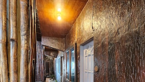 A corridor with bamboo walls, a welcome mat, and a door with a number plate. - MB's Garden Inn (Lapu-Lapu)