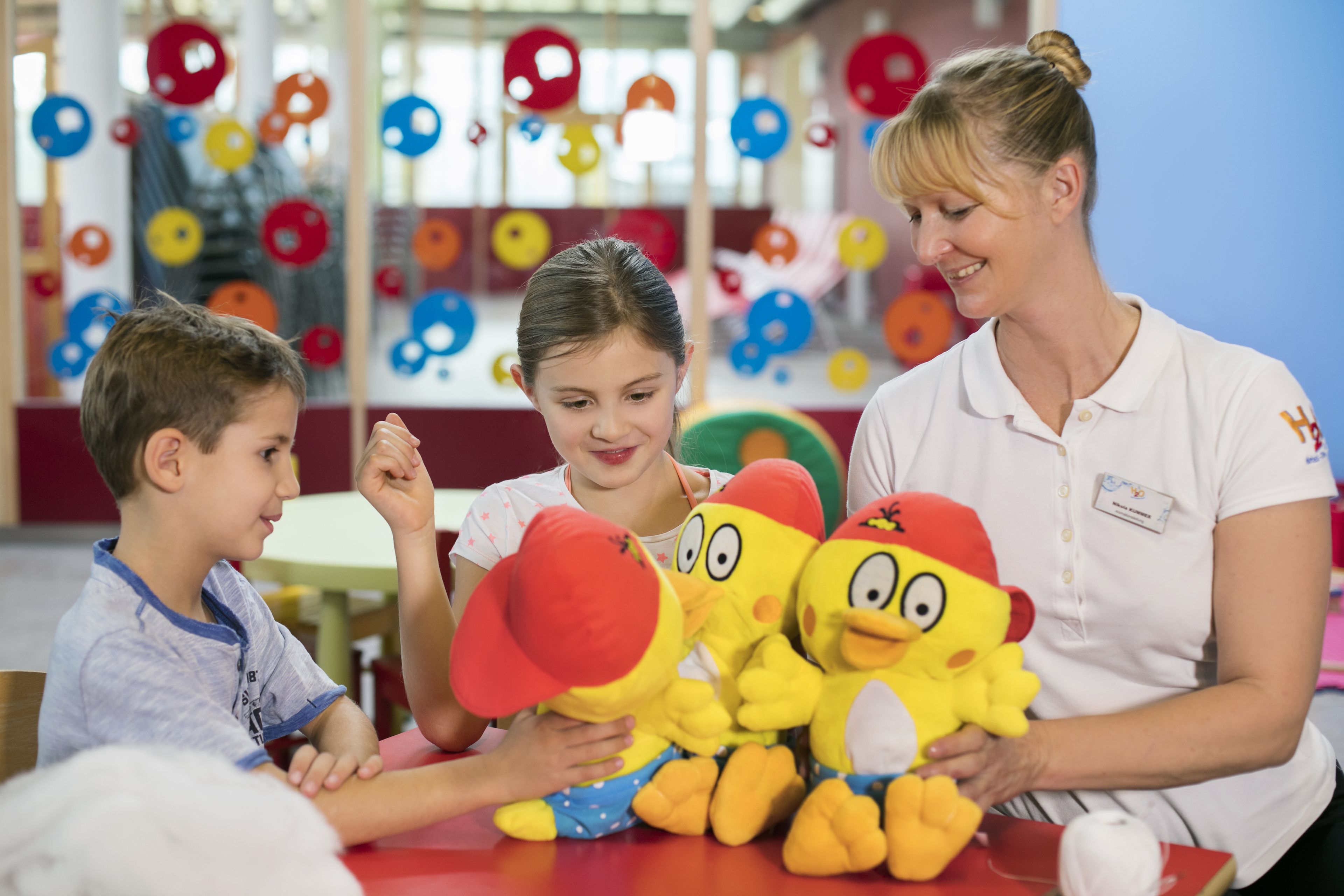 A classroom with children and an adult, colorful decorations, and educational materials.