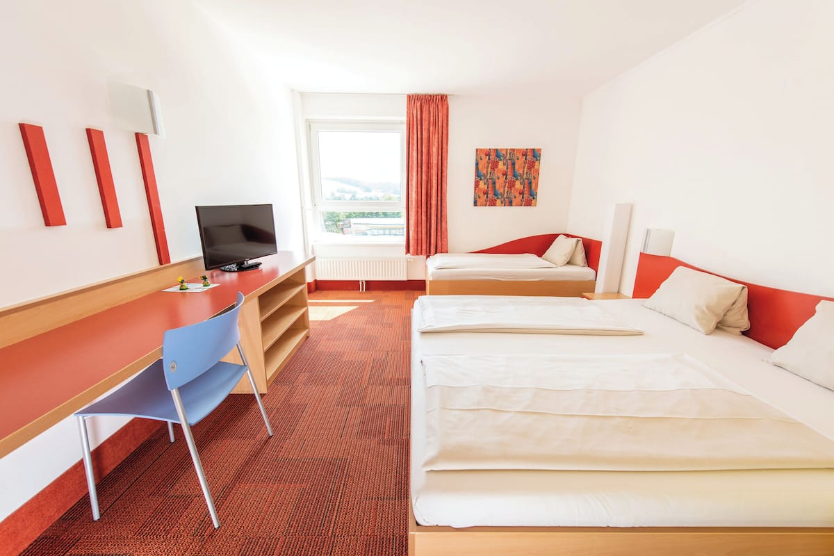 Hotelkamer met een bed, een bureau, een stoel, een televisie en een raam met uitzicht.