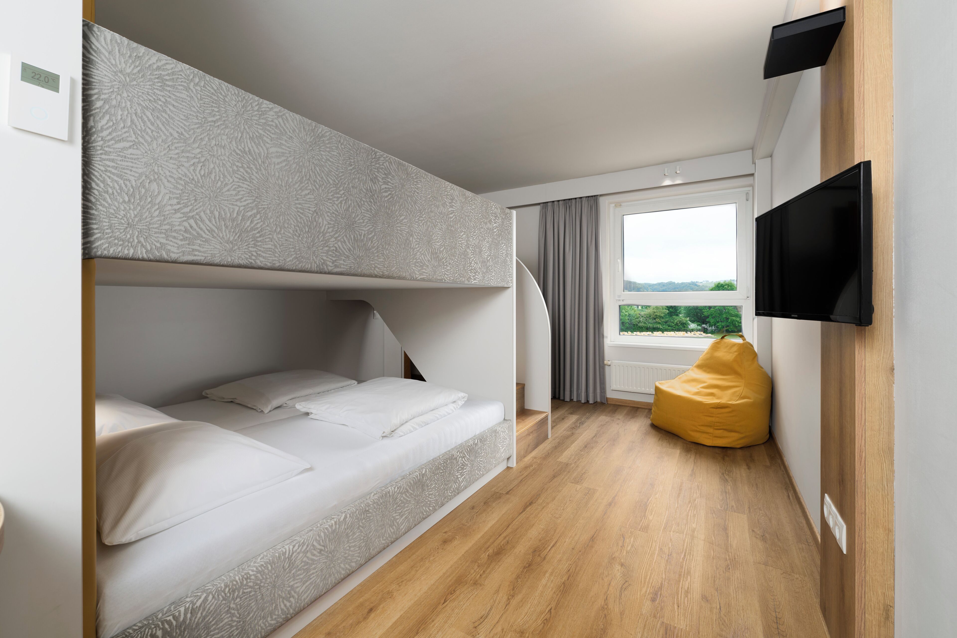 Habitación con literas, televisión, ventana con vistas y un sillón informal.