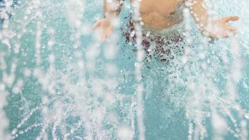 A person swimming in a pool with water splashing around.