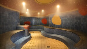 Un espace de bien-être avec des murs recouverts de carreaux bleus, un banc incurvé et une fontaine centrale.