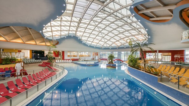 Une piscine intérieure dotée d’un haut plafond et d’une structure en forme de dôme de verre.