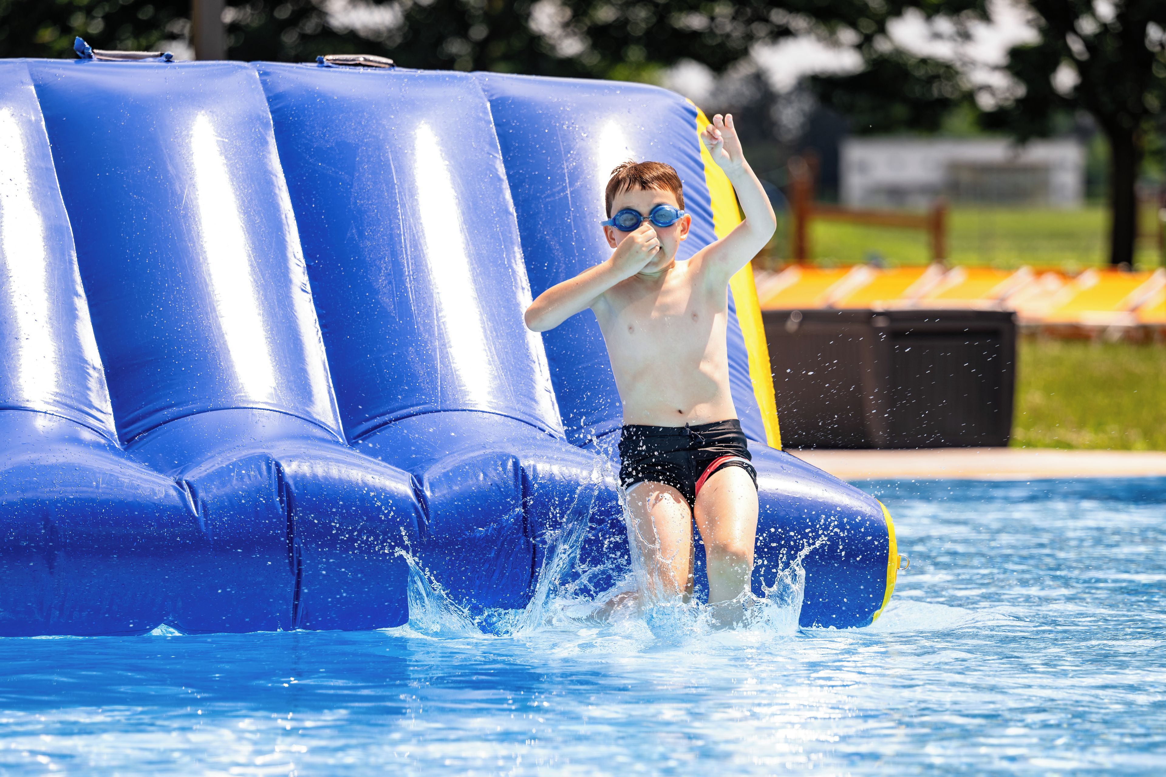 Un niño jugando en una piscina con un tobogán acuático inflable.