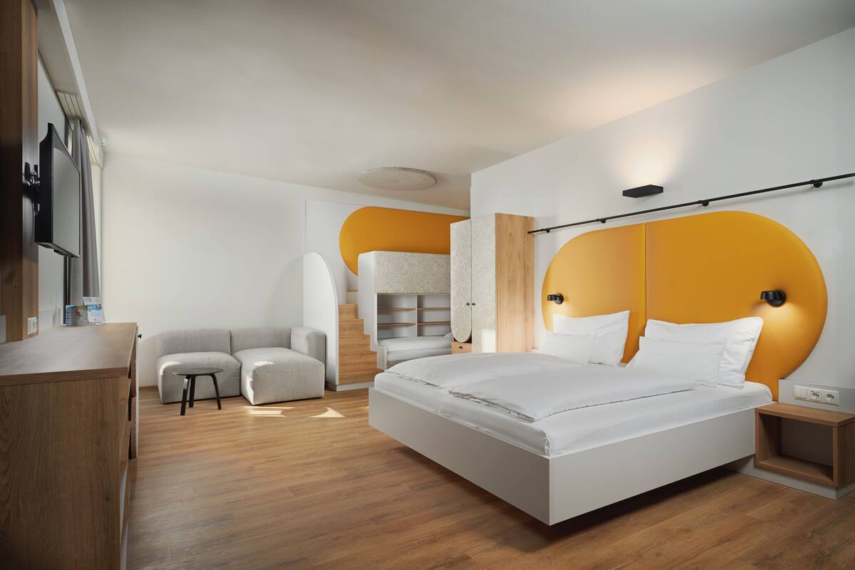 Een moderne slaapkamer met een groot bed, een bank, een stoel en een bureau.