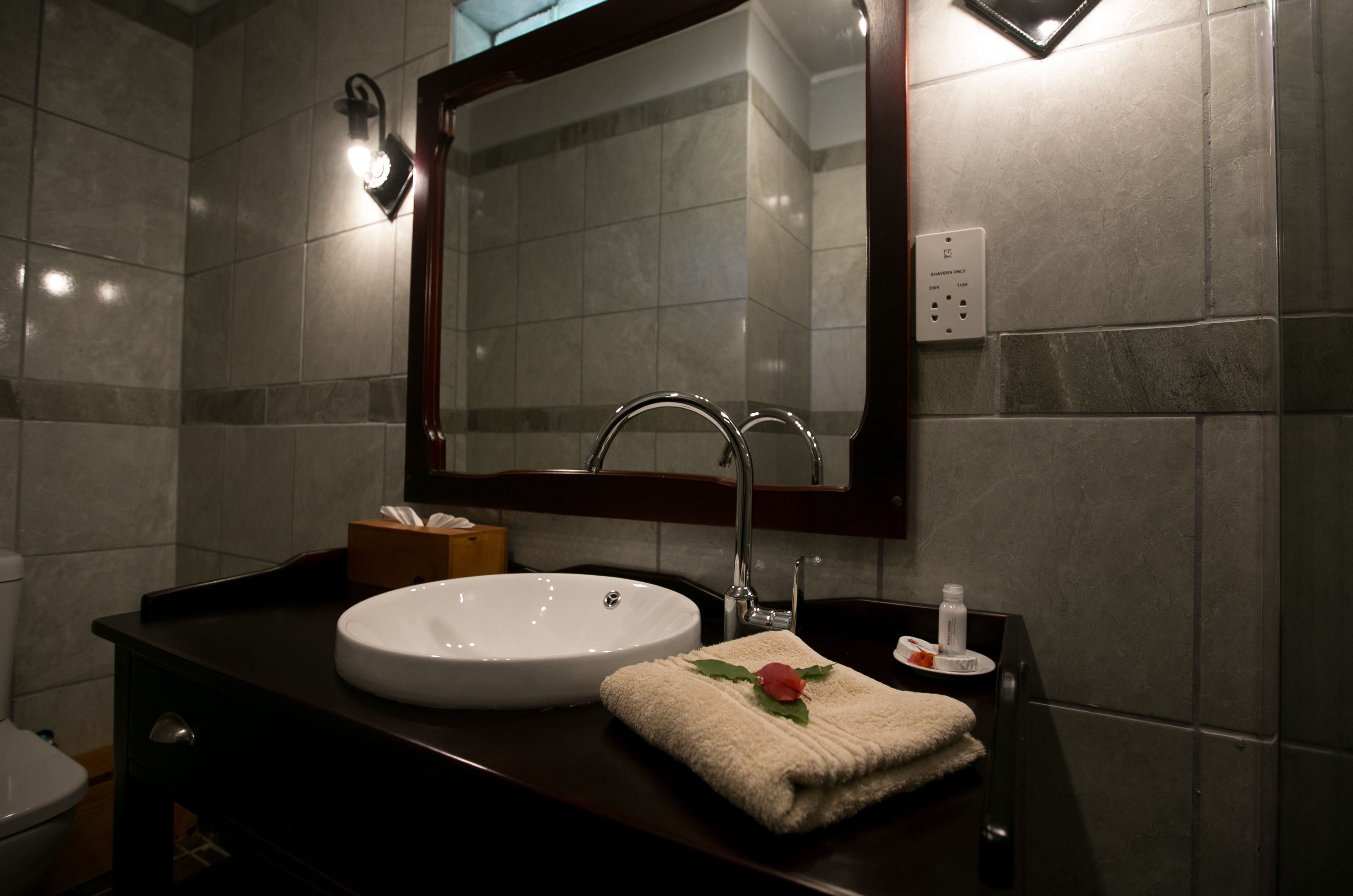 Un baño con lavamanos blanco, encimera oscura y espejo sobre el lavamanos.