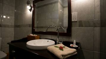 Un baño con lavamanos blanco, encimera oscura y espejo sobre el lavamanos.