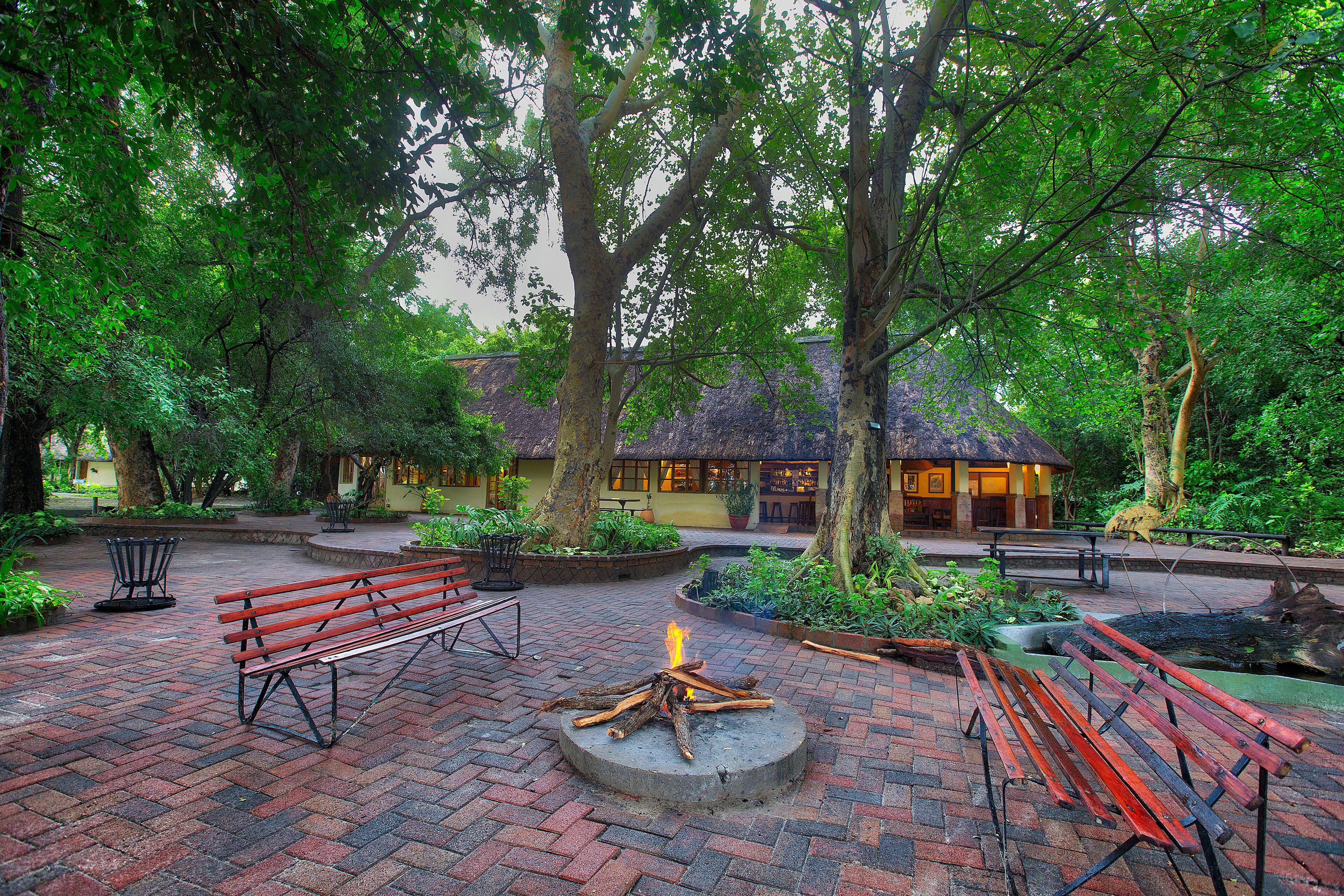 A courtyard with a fire pit, benches, and a building in the background.