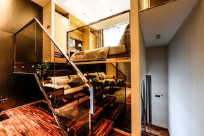Habitación de varios niveles con una litera, un sofá y una escalera.