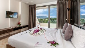 Habitación de hotel con una cama grande, un televisor en la pared y vistas a la montaña.