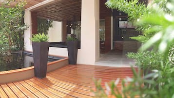 A modern outdoor area with a wooden deck, potted plants, and a water feature.