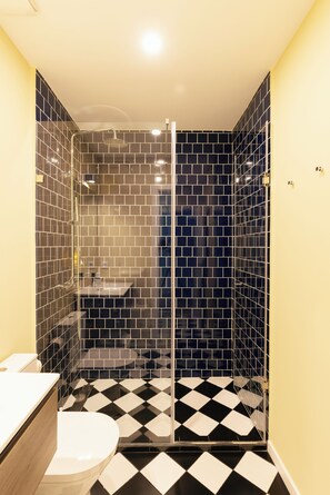 Een badkamer met douche, toilet en wastafel.