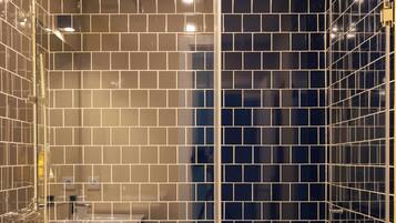 Une salle de bain moderne avec des carreaux noirs et blancs disposés en motif à damier, une douche en verre et un espace lavabo bien visible.
