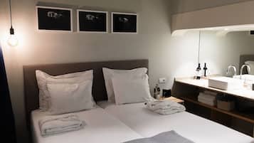 Une chambre d’hôtel avec un lit, une table de chevet avec une lampe, un miroir et trois tableaux encadrés accrochés au mur.