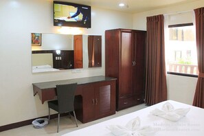 Una habitación moderna de lujo con cama, escritorio, silla, armario, televisor y ventana con cortinas.