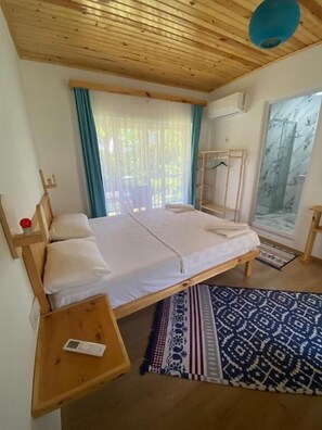 A room with a bed, a bedside table, a window with curtains, and a wall-mounted air conditioning unit. - Harun Mila Pension (Kemer)