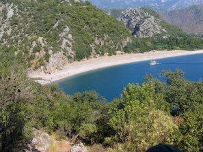 A coastal landscape with a beach, rocky hills, and dense greenery. - Harun Mila Pension (Kemer)