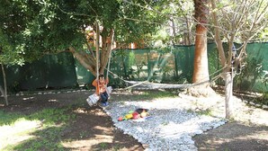 A hammock between trees in a garden with a gravel path and scattered toys. - Harun Mila Pension (Kemer)