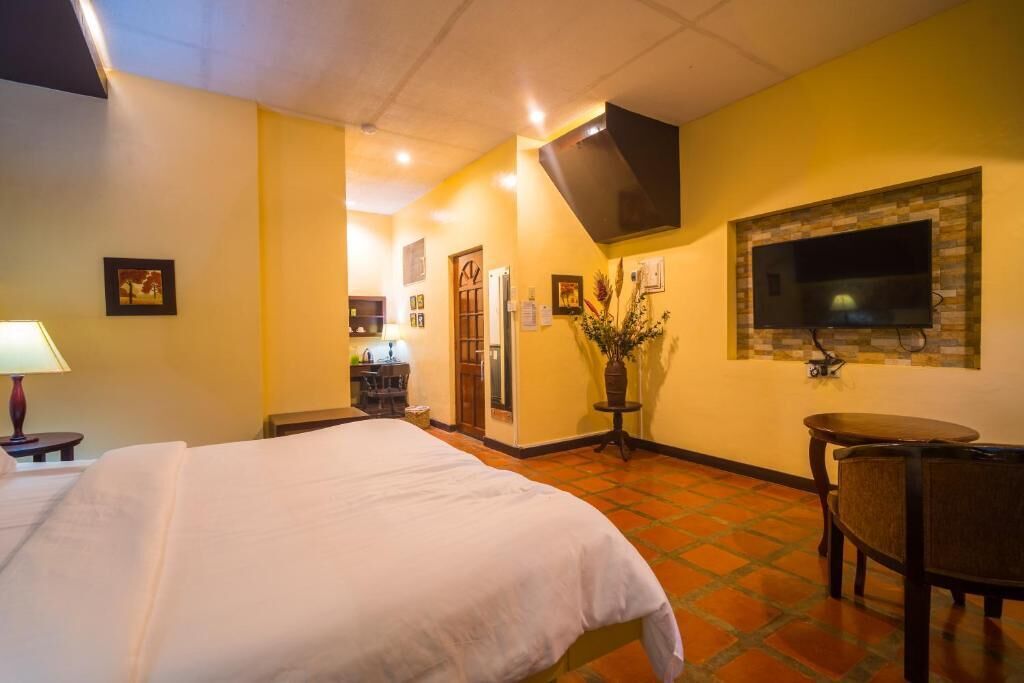 Ein Hotelzimmer mit Bett, Wandfernseher, kleinem Tisch und Stuhl.