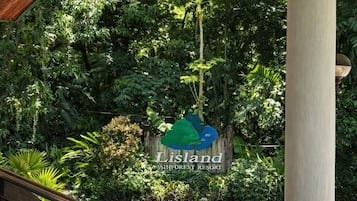 Una escalera conduce a un área techada con un cartel de Lisland Winforest Resort en medio de abundante vegetación.