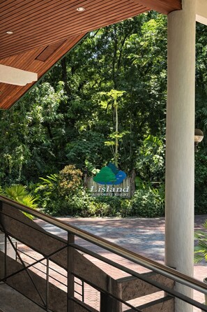 Un escalier mène à une zone abritée où se trouve une enseigne indiquant le « Lisland Winforest Resort », le tout au milieu d’une végétation luxuriante.