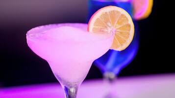Zwei Cocktails in Martini-Gläsern vor einem violetten Hintergrund.
