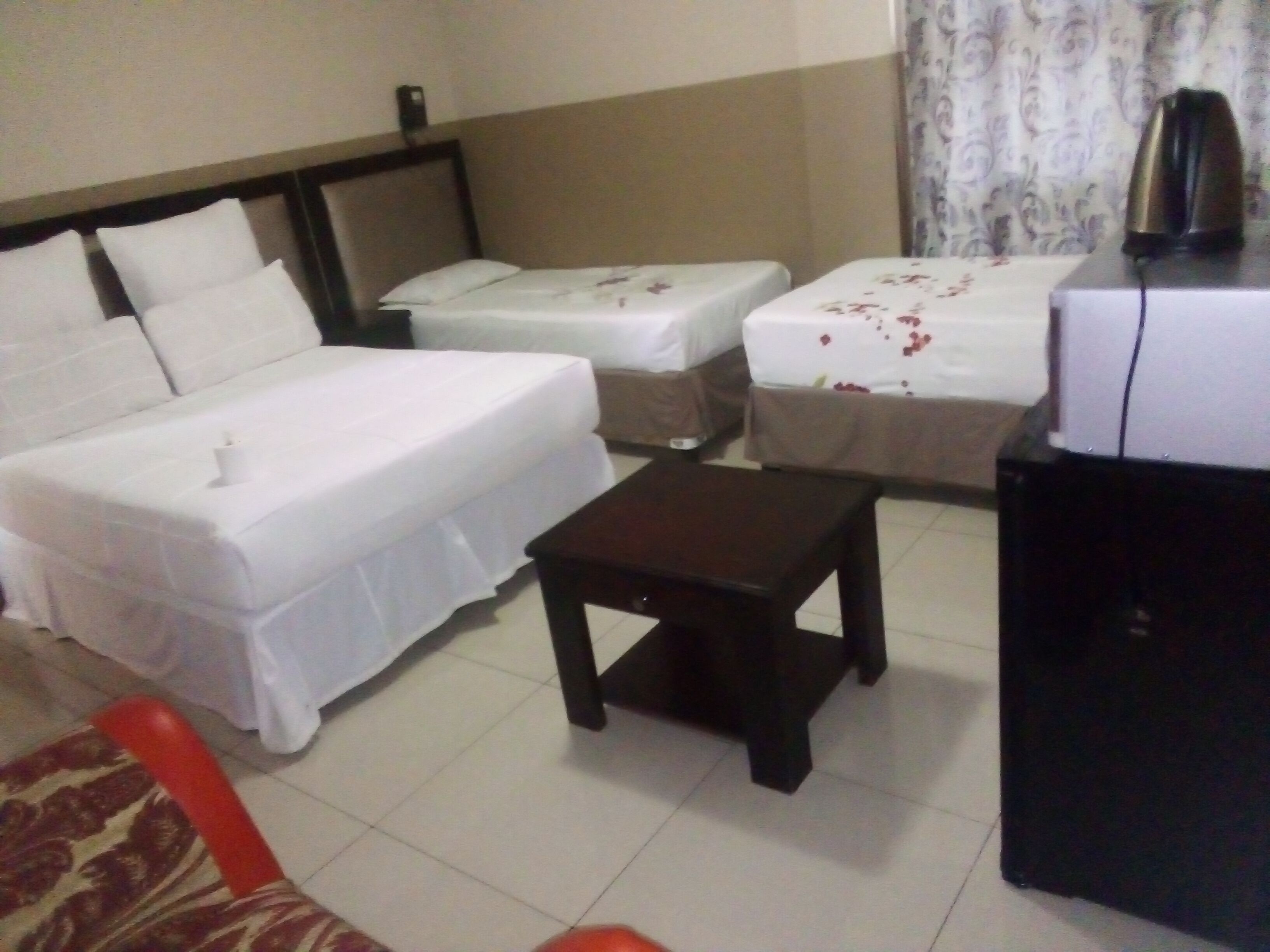 A hotel room with two beds, a small table, and a coffee maker.