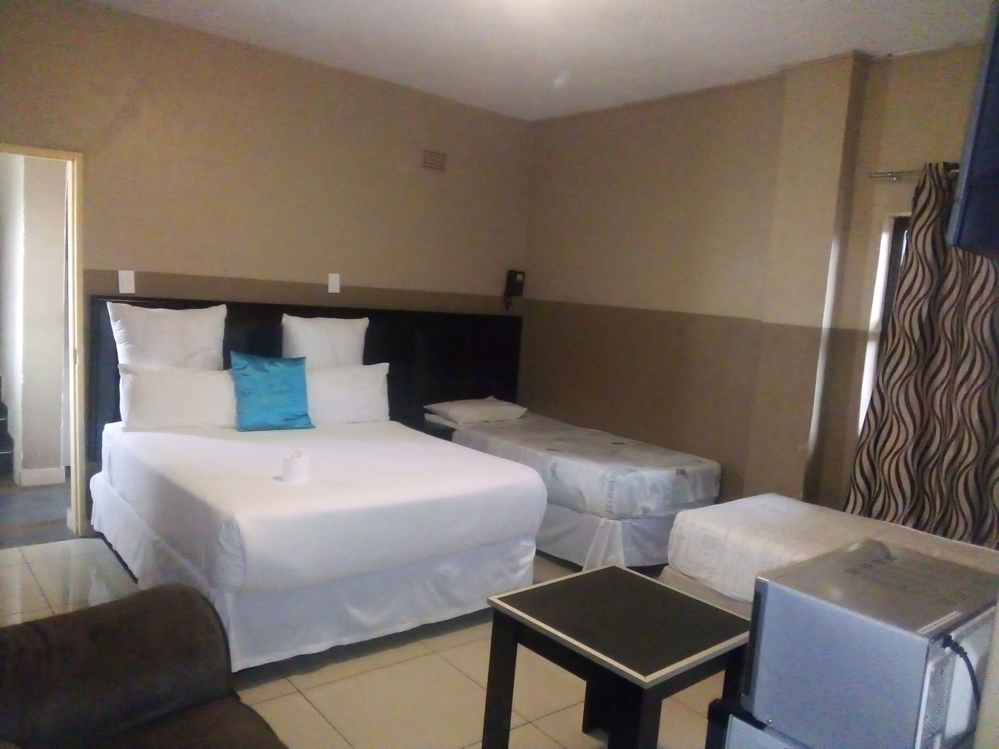 A hotel room with a large bed, a smaller bed, a desk, and a TV.