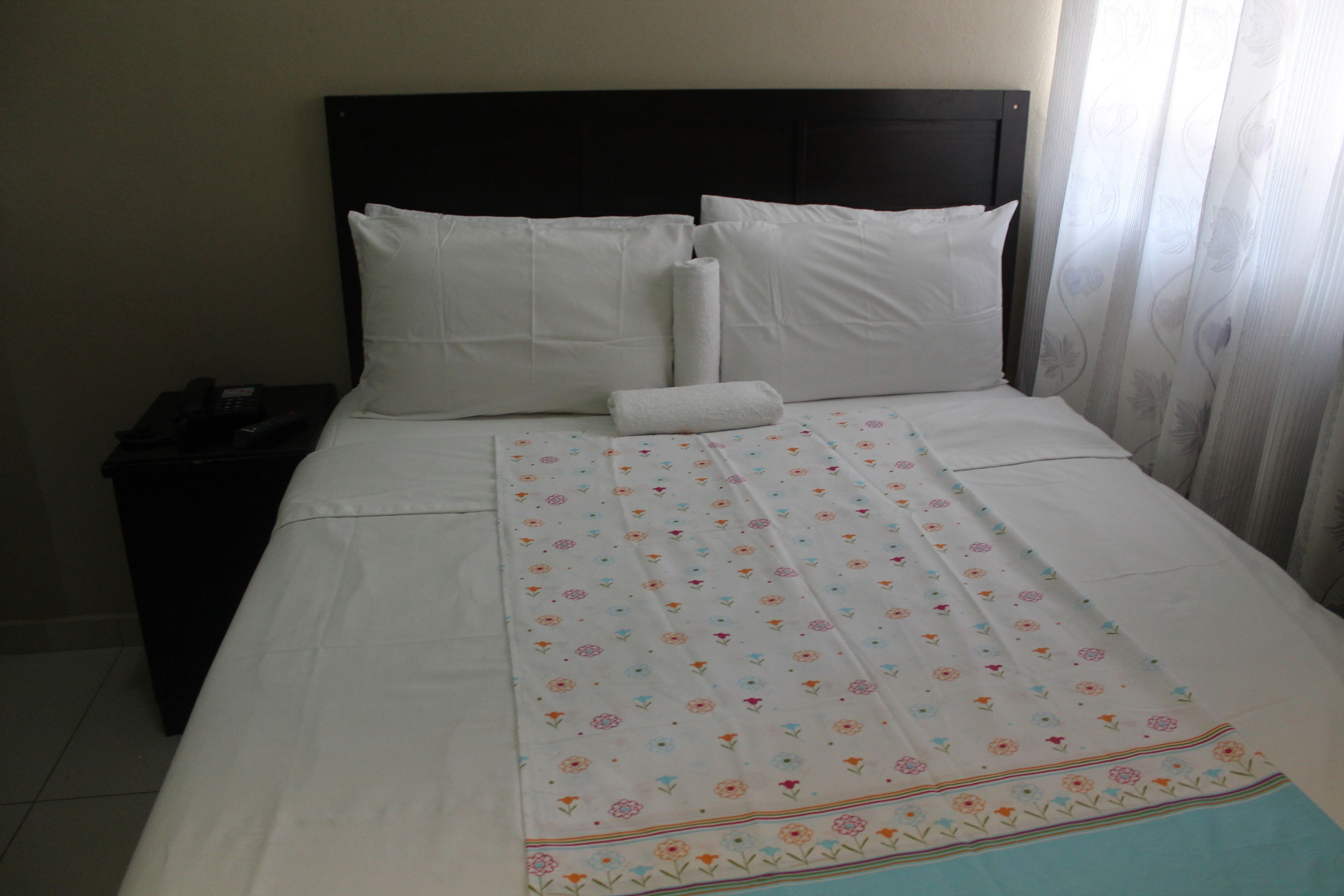 A neatly made bed with white linens and a floral-patterned bedspread.
