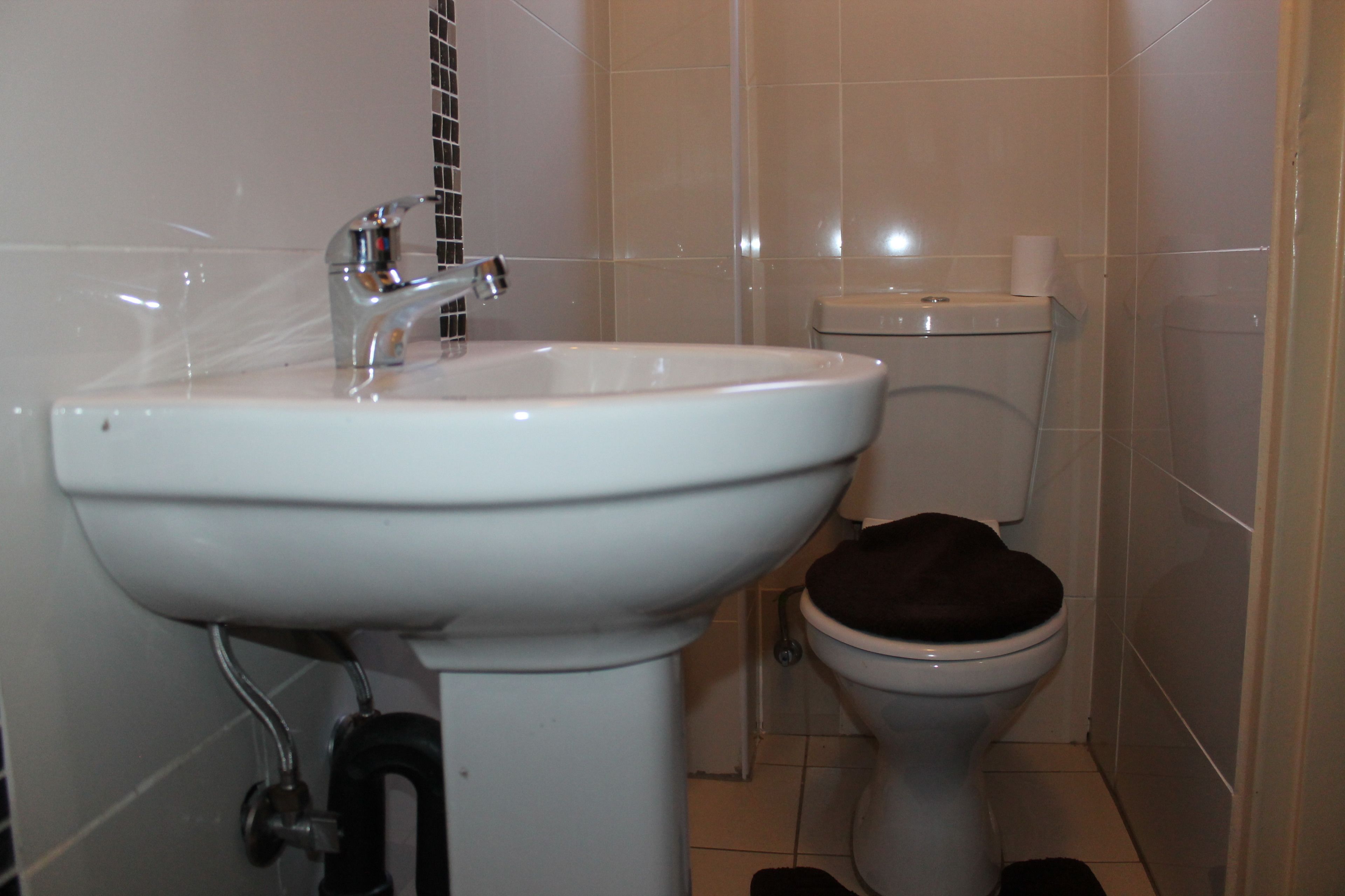A bathroom with a white sink, a toilet, and a tiled wall.