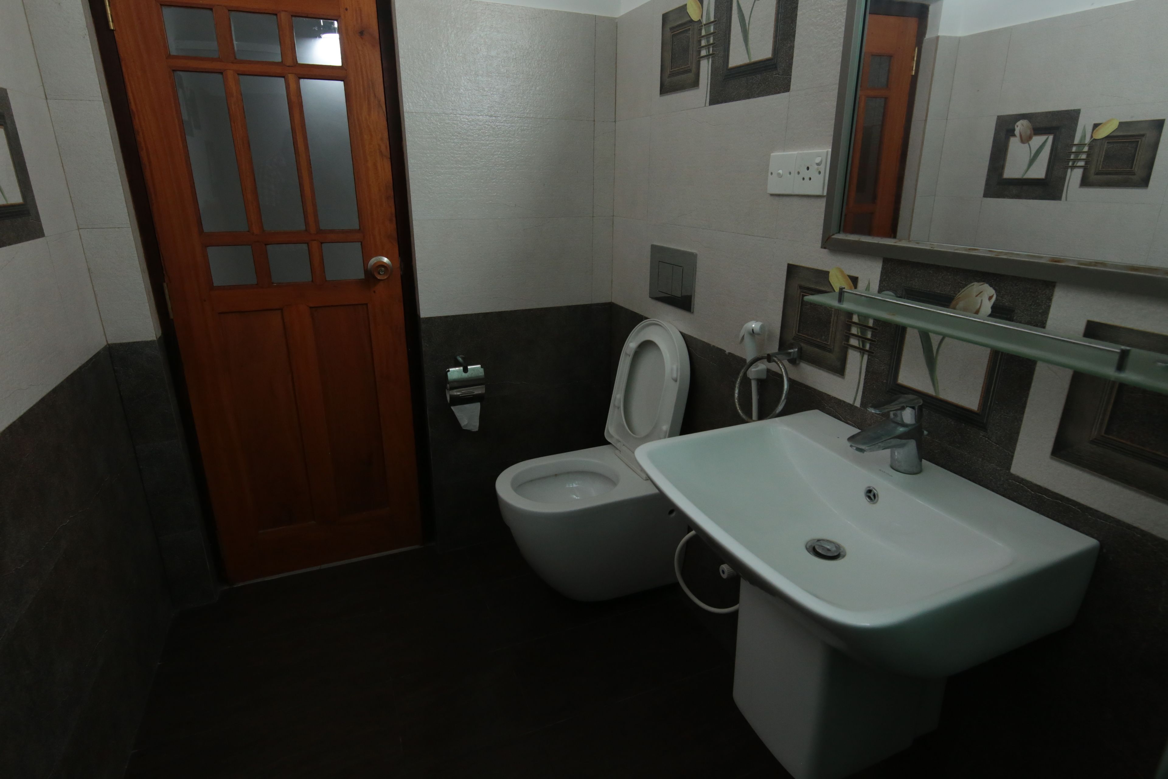 Une salle de bain avec une porte en bois, des toilettes et un lavabo.