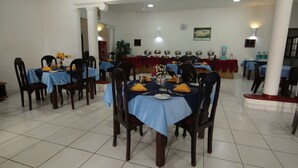 A dining area with multiple tables set with blue tablecloths, chairs, and yellow napkins. - Ocean of Life Ayurvedic Resort (Bentota)