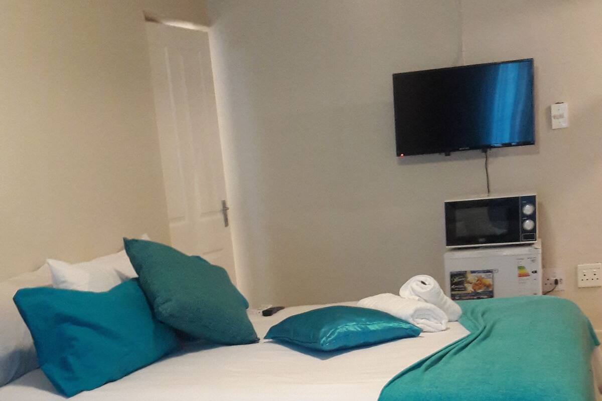 Une chambre d’hôtel équipée d’un lit, d’une télévision et d’un four à micro-ondes.