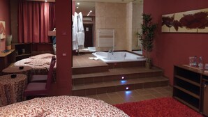 A modern hotel room with a large bed, a sitting area with a table and chairs, a bathroom with a bathtub, and a staircase leading to the upper floor. - Motel Ranch (Gaggiano)