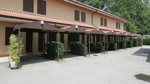 A building with a covered outdoor area, multiple windows, and a tiled roof. - Motel Ranch (Gaggiano)
