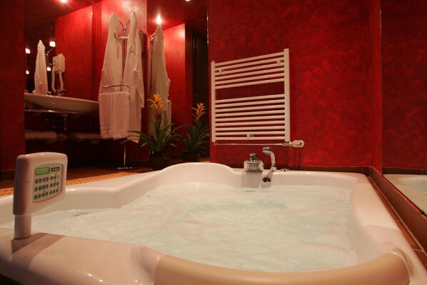 A bathroom with a large bathtub, a towel rack with towels, a sink, and a wall-mounted towel rack. - Motel Ranch (Gaggiano)