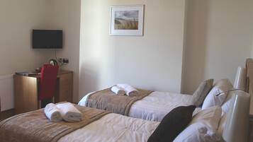 A hotel room with two beds, a desk, a chair, a television, and a framed picture on the wall.
