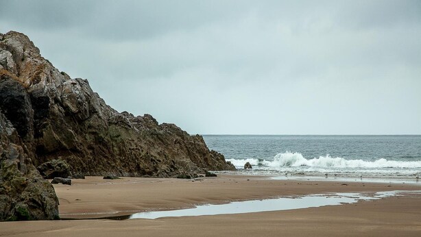A beach with rocky cliffs and waves. - Somerfield Lodge (Swansea)