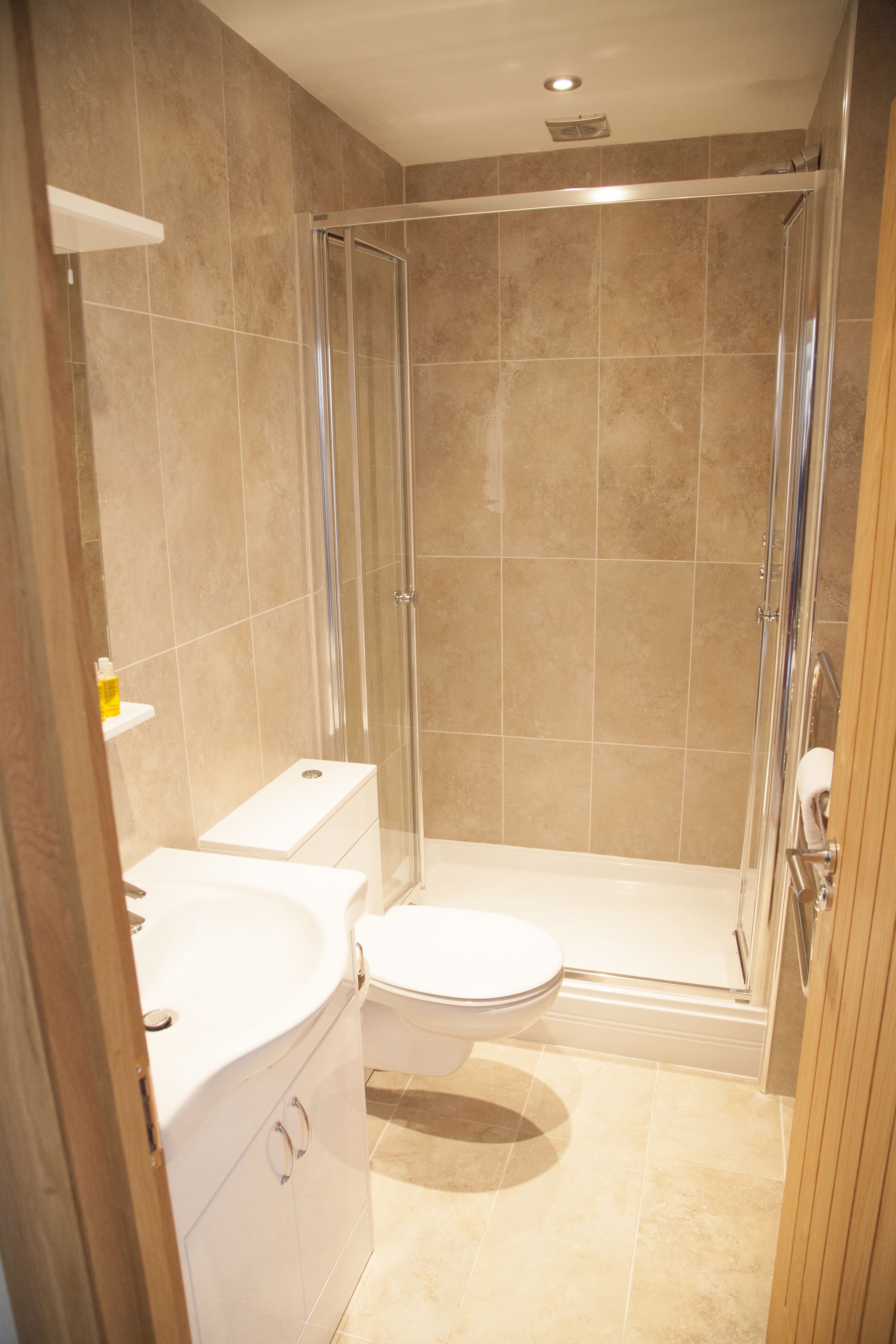 A bathroom with a glass-enclosed shower, a toilet, and a sink.