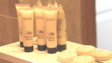 A bathroom shelf with multiple tubes of moisturizing body lotion and a few soap bars.