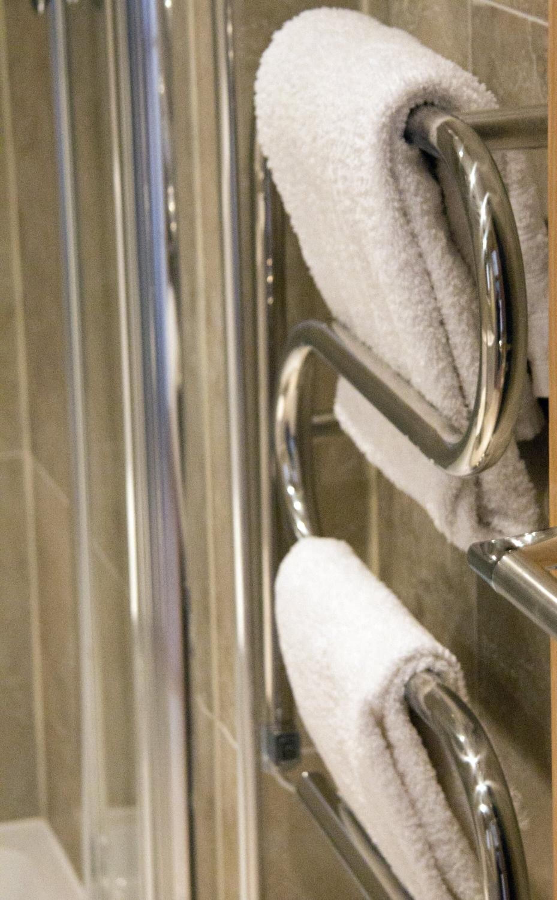 A glass shower enclosure with chrome towel holders.