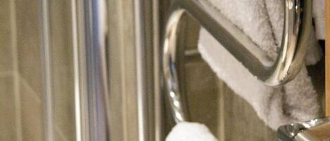 A glass shower enclosure with chrome towel holders.