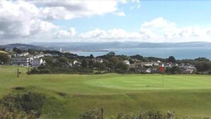 A golf course with a view of the sea and houses in the background. - Somerfield Lodge (Swansea)
