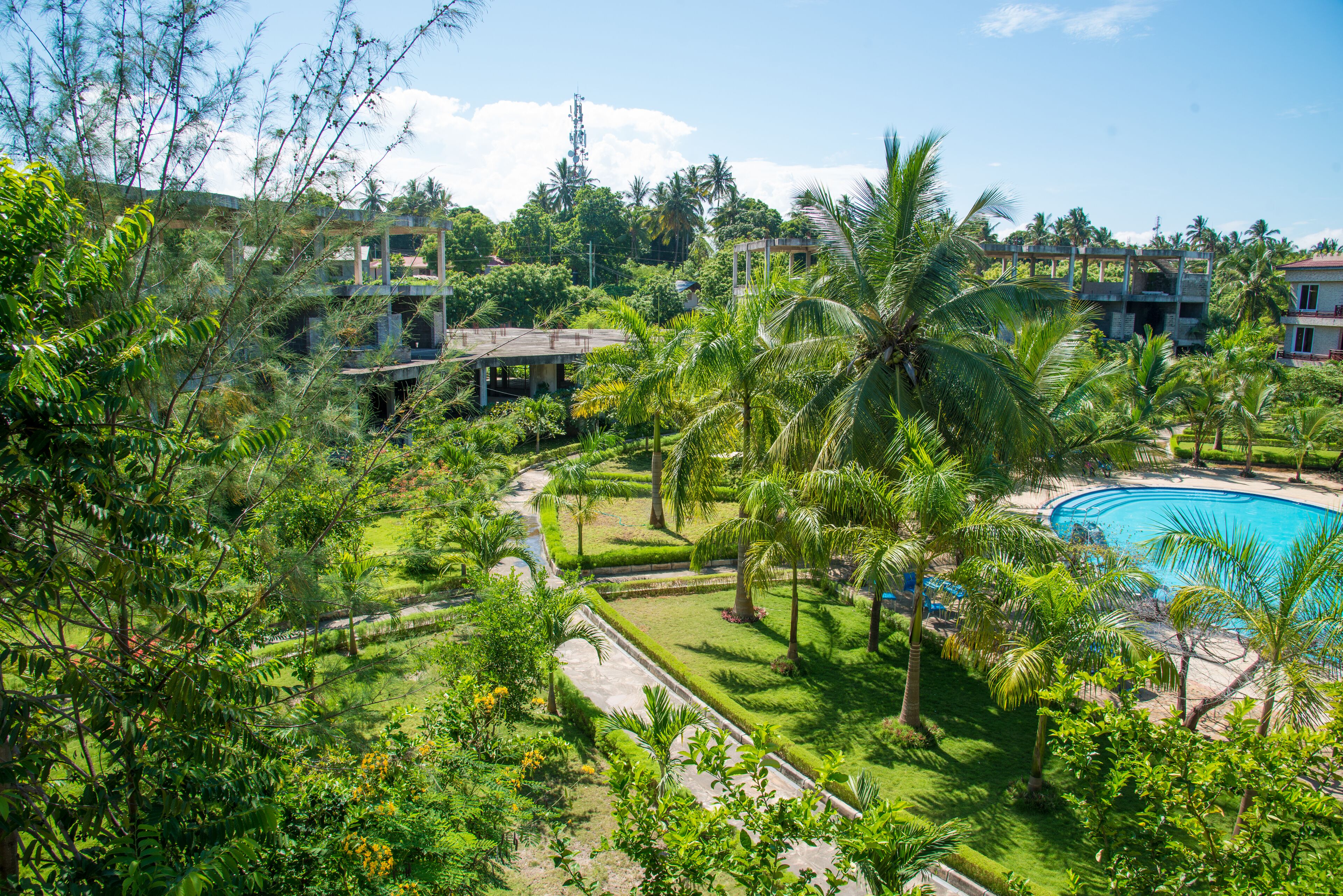 A lush resort with a swimming pool, palm trees, and a well-maintained garden.