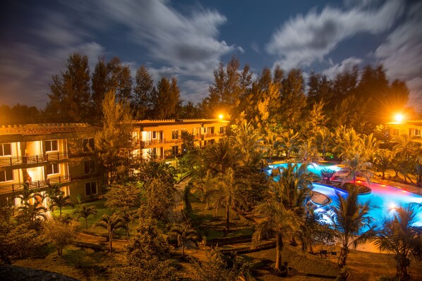 Hotel com várias varandas, piscina e vegetação exuberante.
