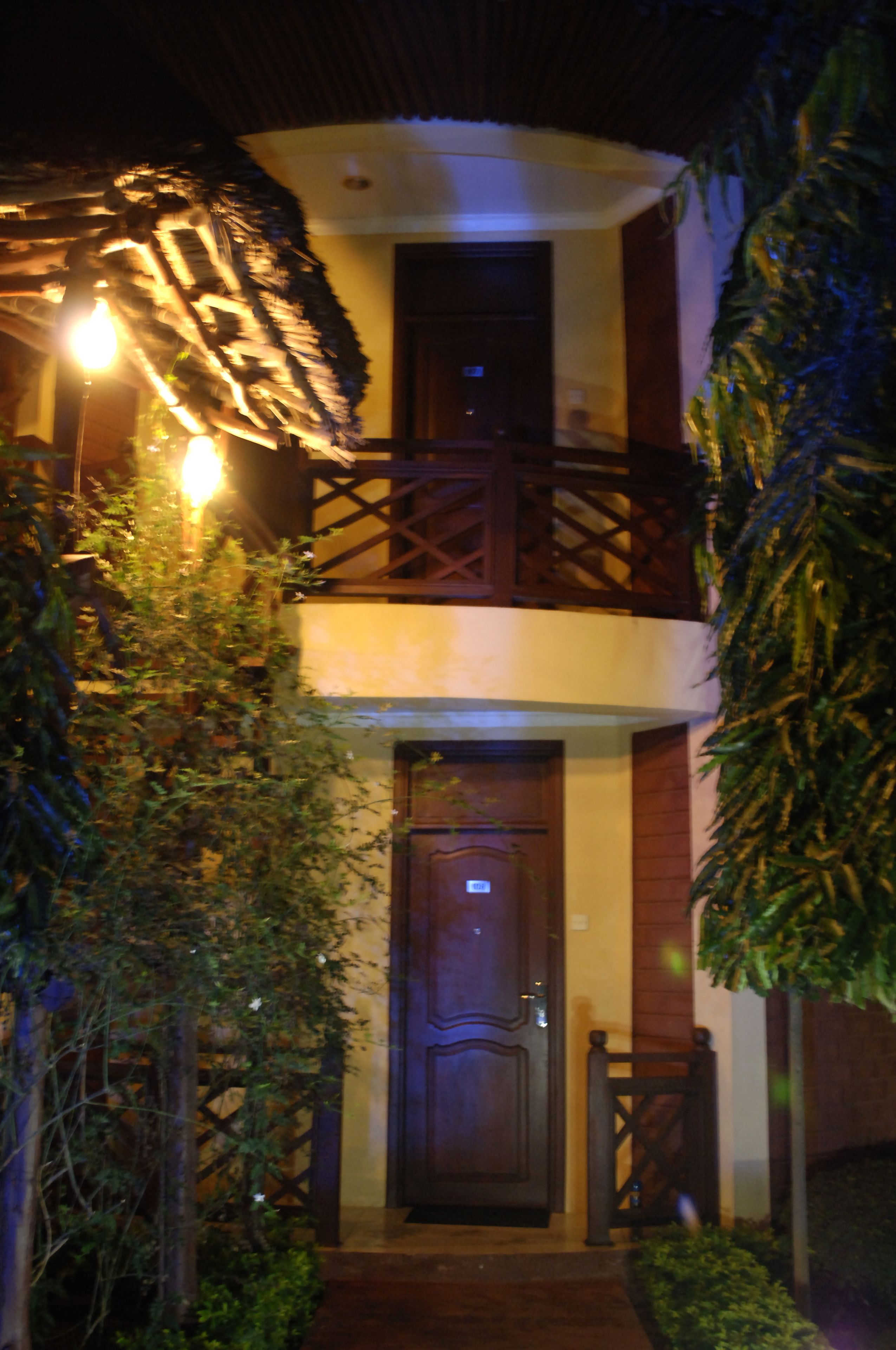 A two-story building with a wooden balcony and a dark wooden door.
