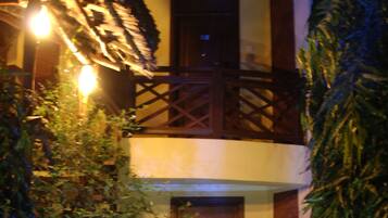 A two-story building with a wooden balcony and a dark wooden door.
